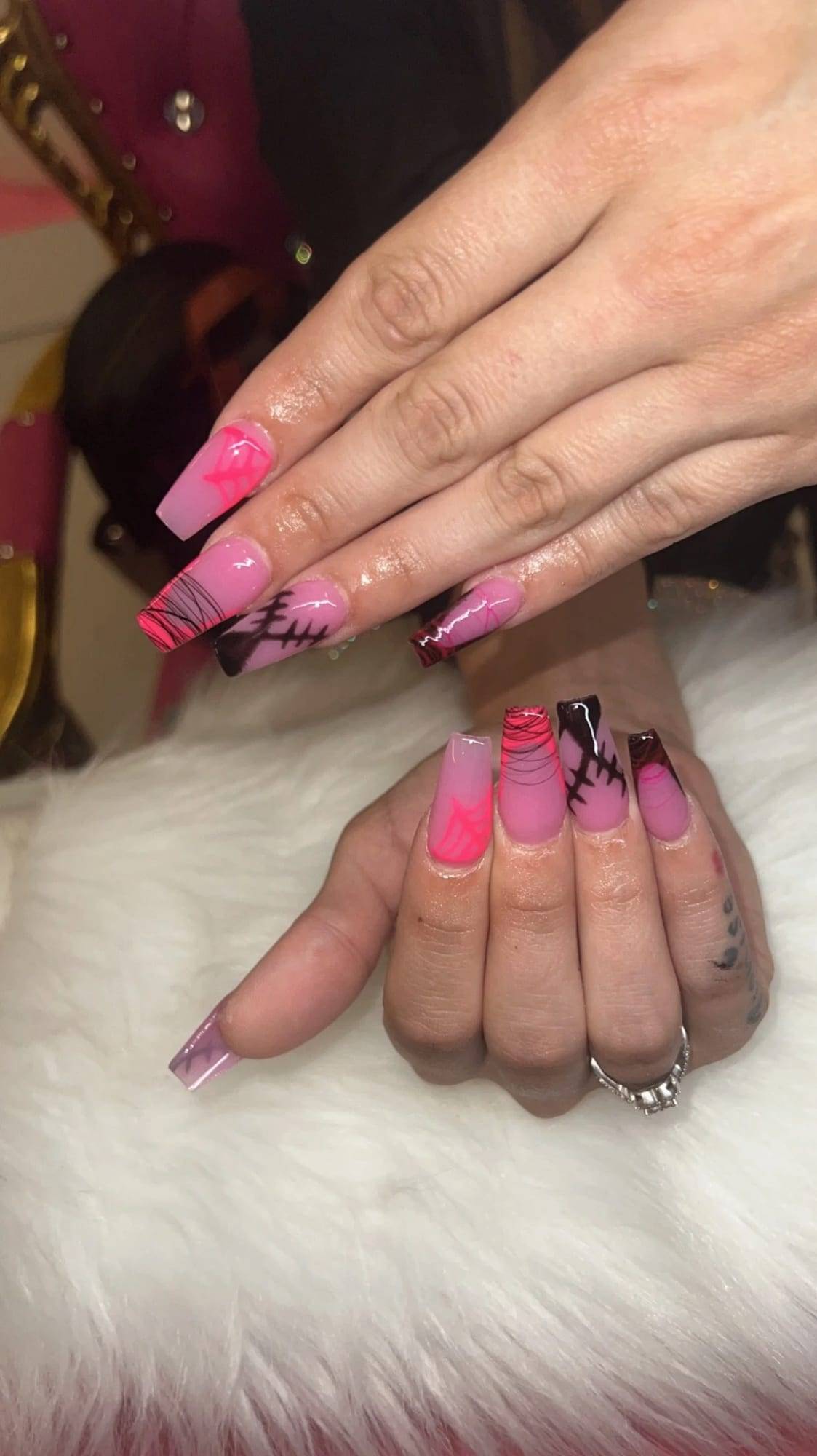 Coffin acrylics in hot pink with black accents on a white fur rest